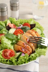 Eating delicious salad with chicken and vegetables at table, closeup