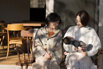 赤ちゃんを抱っこする母親と見守る祖母　同居や子育てなどのイメージ