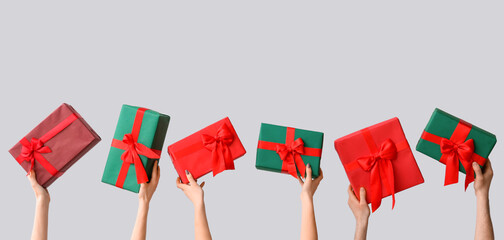 Many hands with Christmas gifts on grey background