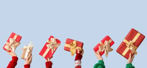 Many hands with Christmas gifts on light background