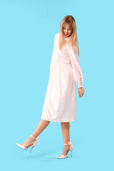 Young woman dressed as doll on blue background