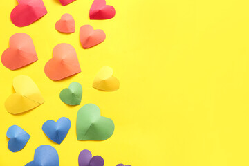 Colorful paper hearts on yellow background. LGBT concept