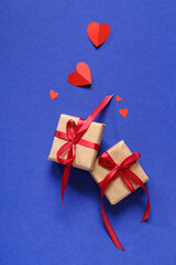 Composition with gift boxes and red paper hearts on blue background. Valentines Day celebration
