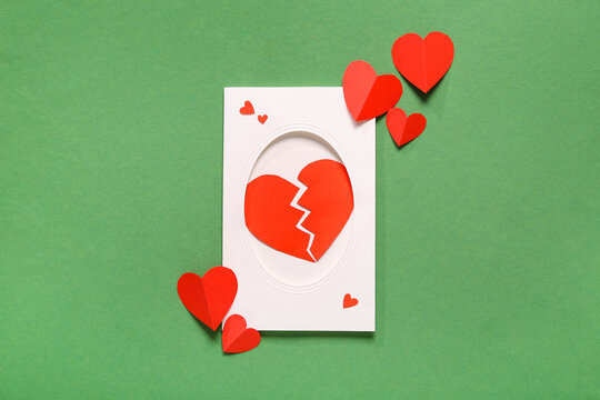 Composition with card and red paper hearts on green background. Valentines Day celebration