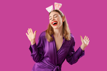 Beautiful young stylish woman in bunny ears on purple background