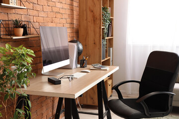 Blank computer monitor with stationery on table in office