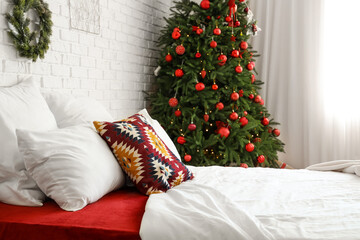 Interior of light bedroom with big bed and Christmas tree