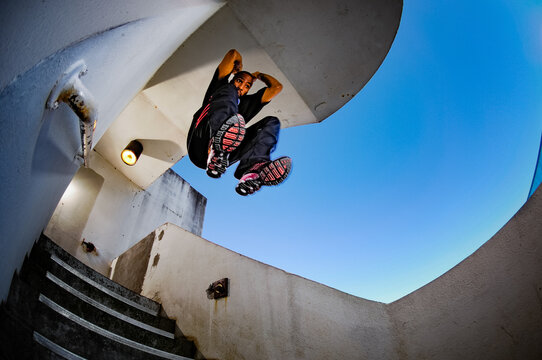 A man practices parkour, jumping down a flight of stairs in a parking deck in Decatur, Georgia