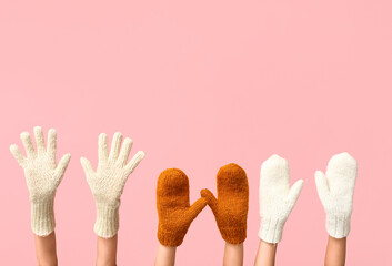 Hands in warm gloves and mittens on pink background