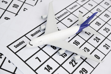 Airplane model on calendar page.  Flight schedule and travel concept. 