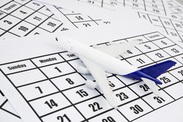 Airplane model on calendar page. Flight schedule and travel concept.