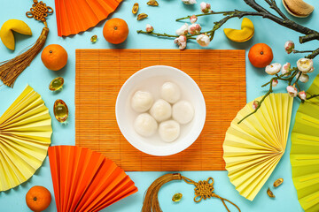 Bamboo mat with bowl of tangyuan, mandarins, Chinese decor and sakura on blue background. Dongzhi...