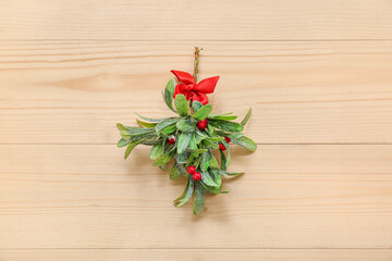 Mistletoe branch with ribbon on light wooden background