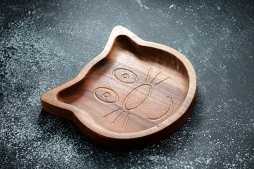 Tuinposter A plate for children in the shape of a cat is made of wood for serving snacks, fruits, nuts, cheeses, meat and original serving of main dishes. Accessories for a modern kitchen. © INTHEBLVCK