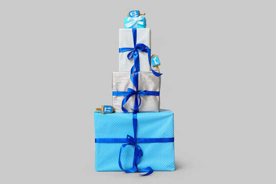 Stack of different gifts for Hanukkah celebration and dreidels on grey background