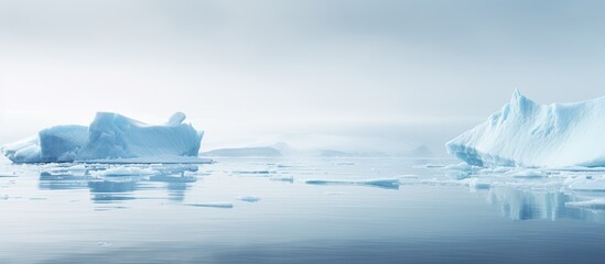 Icy winter landscape with foggy weather, pure ice chunks, drifting from melting glacier in calm water, resemble blue icebergs in ocean.