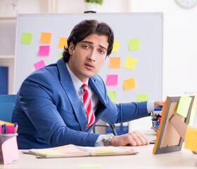 Young male handsome employee in conflicting priorities concept