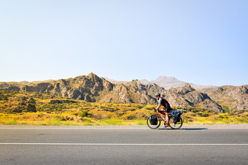 Side view caucasian male cyclist bicycle touring on flat asphalt in caucasus mountains. Active...