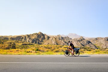 Fotobehang Side view caucasian male cyclist bicycle touring on flat asphalt in caucasus mountains. Active inspirational lifestyle concept. Carefree cyclist lifestyle. Cycle around the world © Evaldas