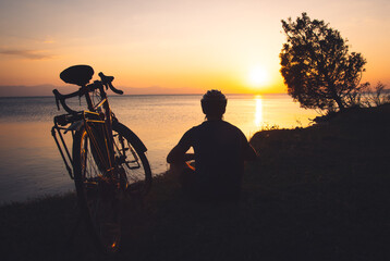 Cyclist enjoy panoramic view of lake outdoors on sunset. Healthy lifestyle and bicycle touring....