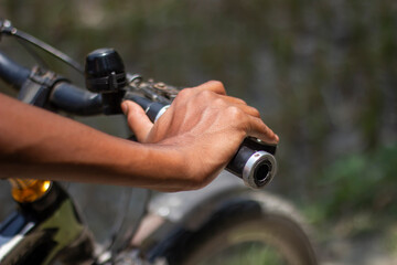A man is holding a bicycle handle with his hands and a blurred background