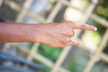 A man has two fingers on his hand pointing forward and blurred background