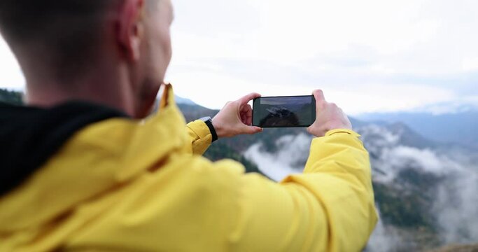 Male traveler taking pictures on mobile phone mountains 4k movie slow motion. Hobby photographing nature concept