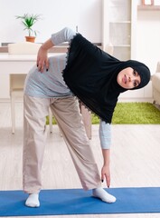 Young woman in hijab doing exercises at home