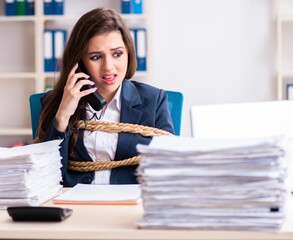 Young beautiful employee tied up with rope in the office