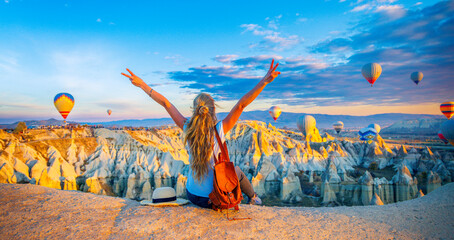 Happy woman enjoying panoramic view of Cappadocia landscape and colorful hot air balloons in the...