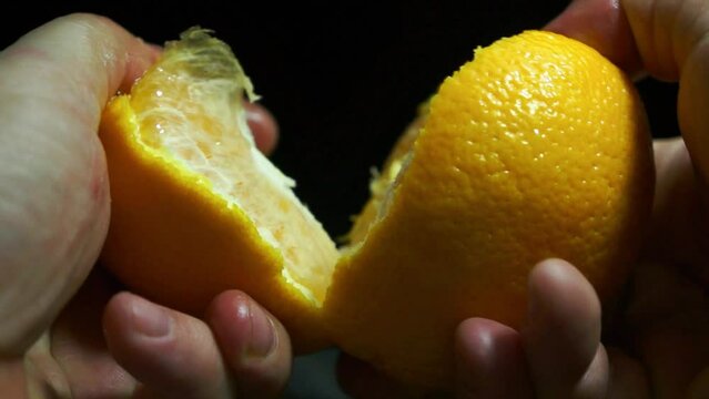 a close-up of the orange bursting with two hands