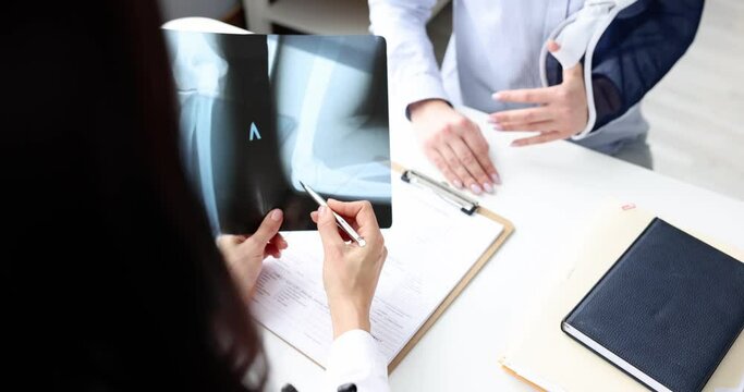 Doctor examines an X-ray of patient with broken arm. Bone injury concept