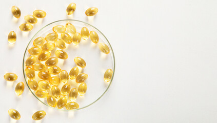 Yellow pills in petri dish on white background. Omega.