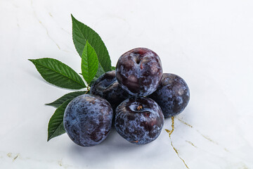 Raw purple plums heap with leaves