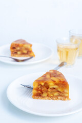 Sliced of homemade apple tarte tatin or apple pie on white ceramic plate.