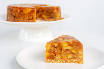 Sliced of homemade apple tarte tatin or apple pie on white ceramic plate.