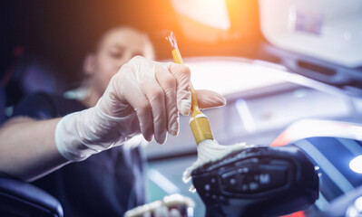 Young woman cleaning the car interior using a special brush with foam