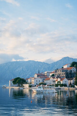 Fototapeta na wymiar Tourist boat is moored to the coast of Perast against the backdrop of mountains. Montenegro