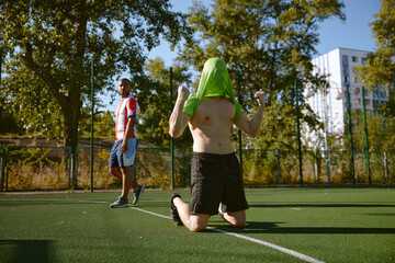 Street football on city soccer field with focus on sportsman celebrating goal