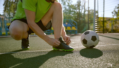 Amateur soccer player tying shoelaces before training closeup