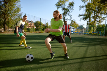 Sportsman team playing football on field at countryside