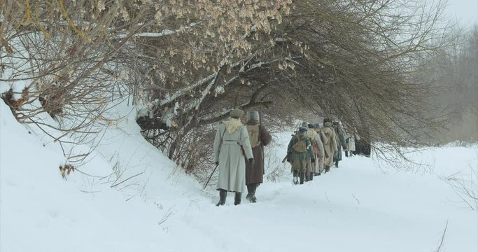 Men Dressed As White Guard Soldiers Of Imperial Russian Army In Russian Civil War s Marching Through Snowy Winter Forest. Historical Reenactment of Civil War. Army Squad on Marching.