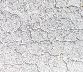 Cracked plaster on a white wall as an abstract background. Texture