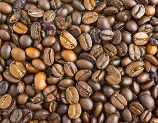 Fototapeta premium Close up of a bunch of coffee beans background top view; roasted dark brown coffe seeds