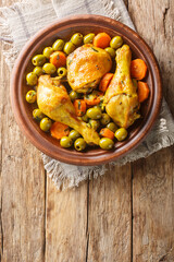 Traditional Algerian Meal Tajine Zitoune of chicken, carrots and green olives close-up on wooden...