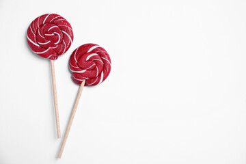 Sticks with bright lollipops on white background, flat lay. Space for text