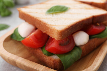 Delicious Caprese sandwich with mozzarella, tomatoes, basil and pesto sauce on table, closeup