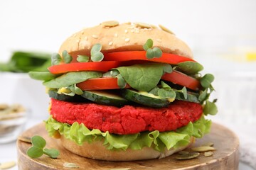 Tasty vegan burger with vegetables, patty and microgreens on wooden board, closeup