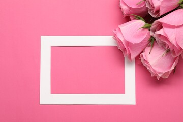 Beautiful roses and frame on pink background, top view. Space for text