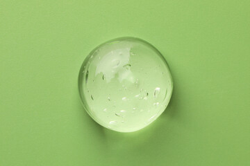 Sample of clear cosmetic gel on light green background, top view